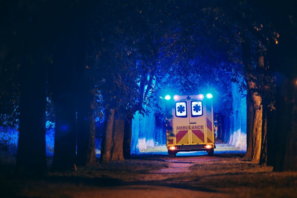 Ambulance with lights on driving on a drive way.